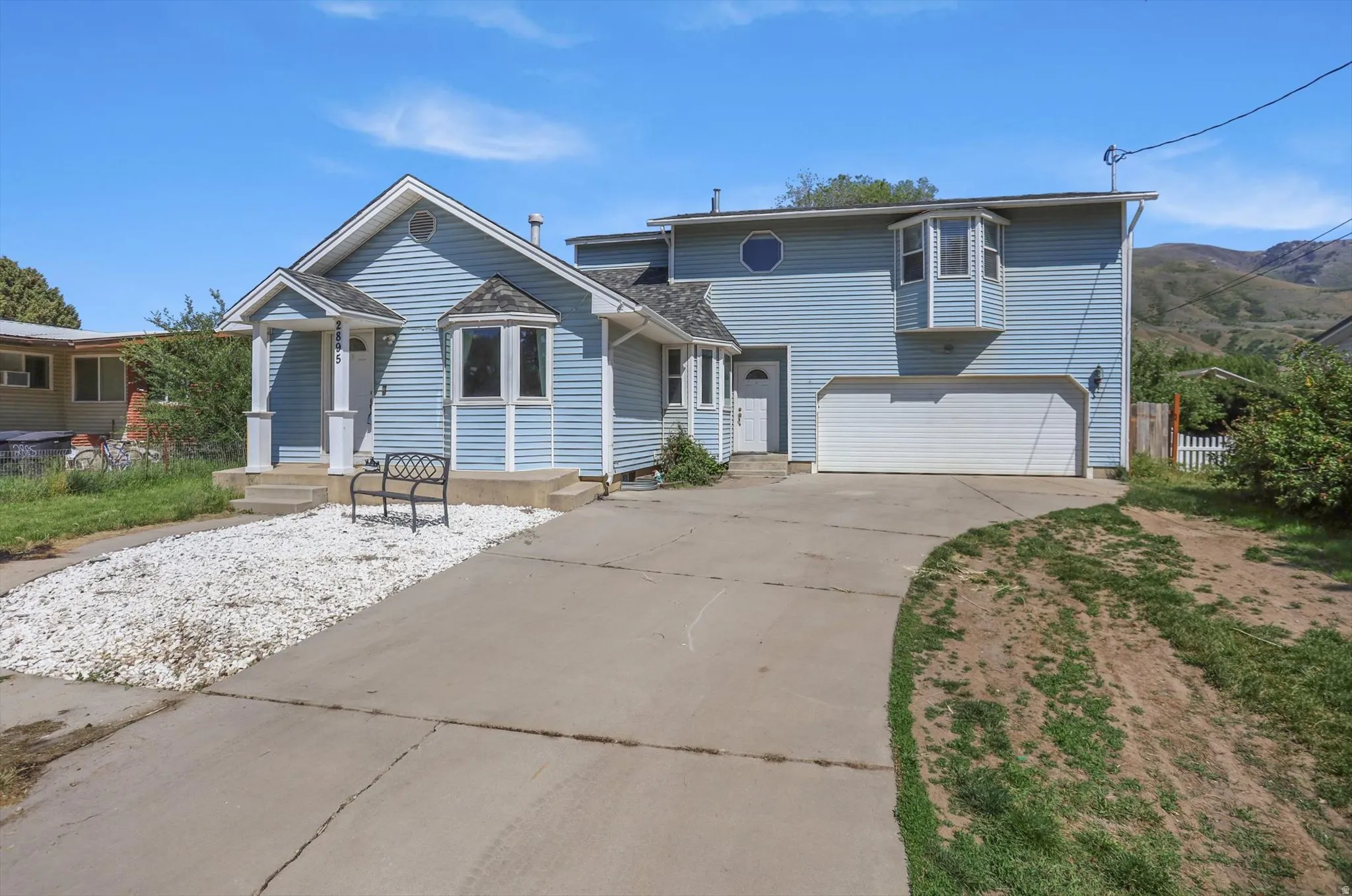 Light blue siding exterior featuring a covered entry, bay window, two-car garage, and a circular window accent