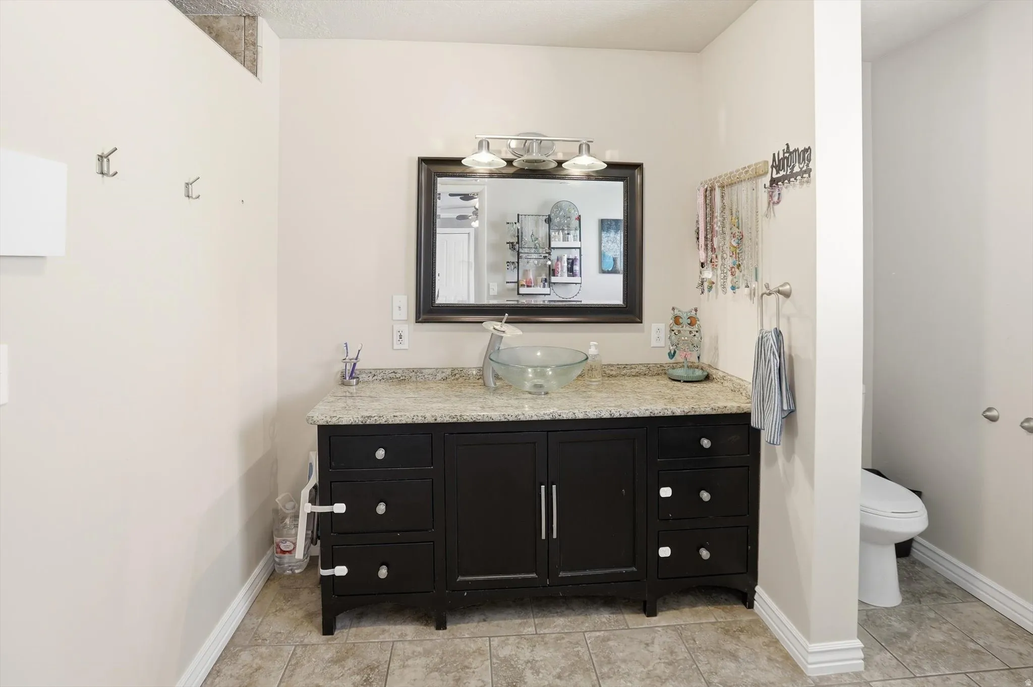 Bathroom vanity featuring a dark wood cabinet, vessel sink, and light-toned countertop