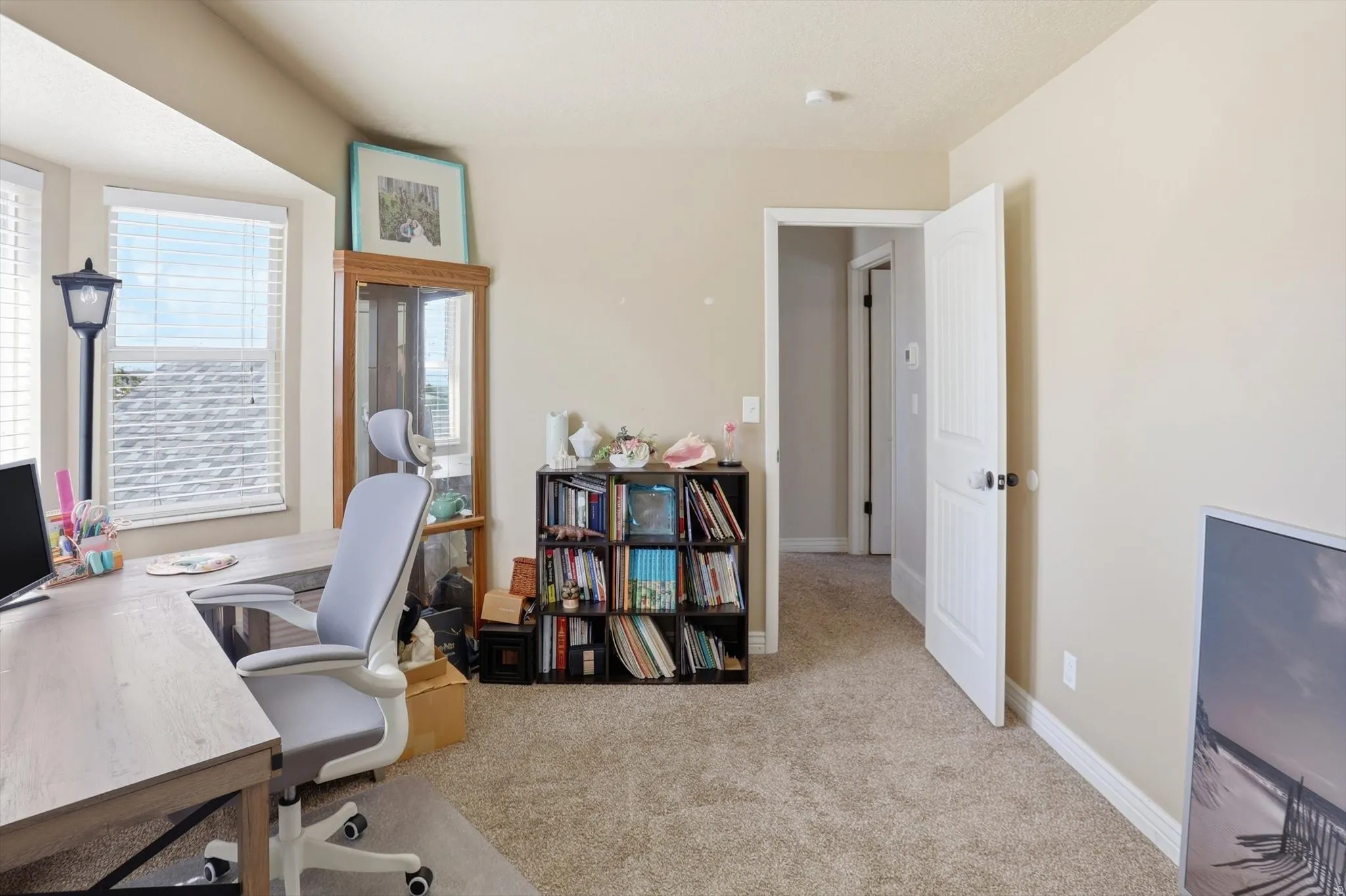 Carpeted room featuring a bay window, neutral wall paint, white trim, and a paneled interior door with black hardware