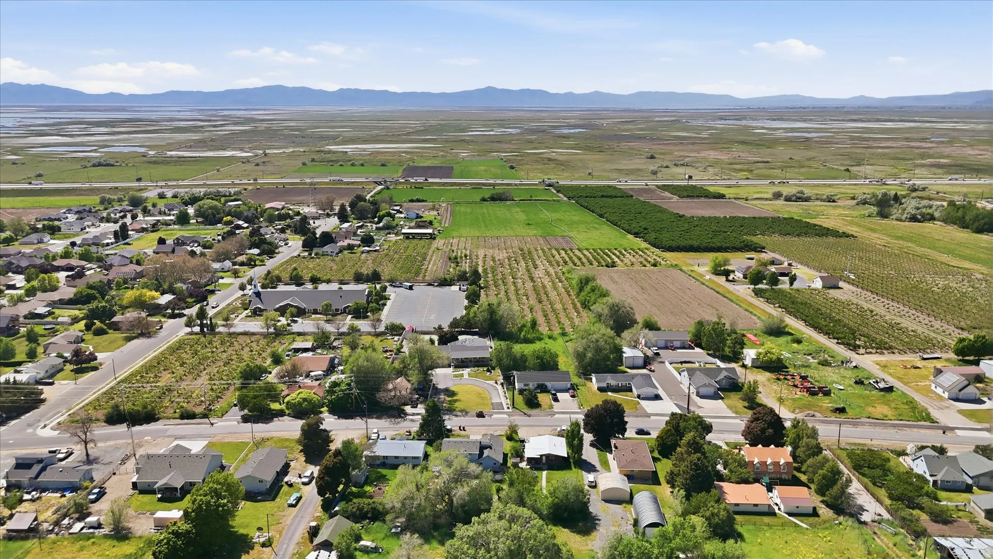 Aerial perspective showcasing a residential area bordered by cultivated agricultural fields and distant natural terrain