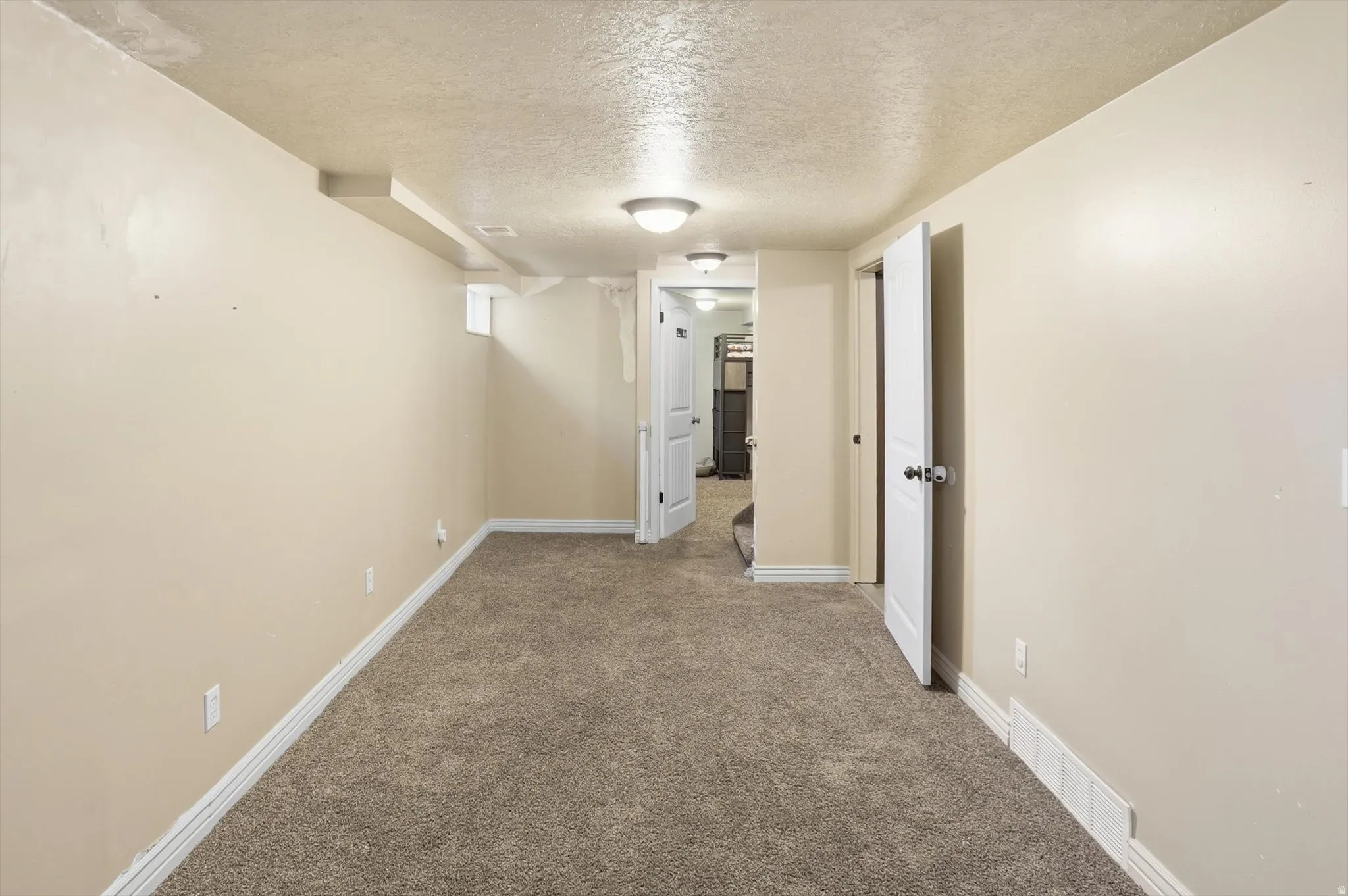 Carpeted room featuring neutral wall paint, white baseboards, and overhead flush-mount lighting