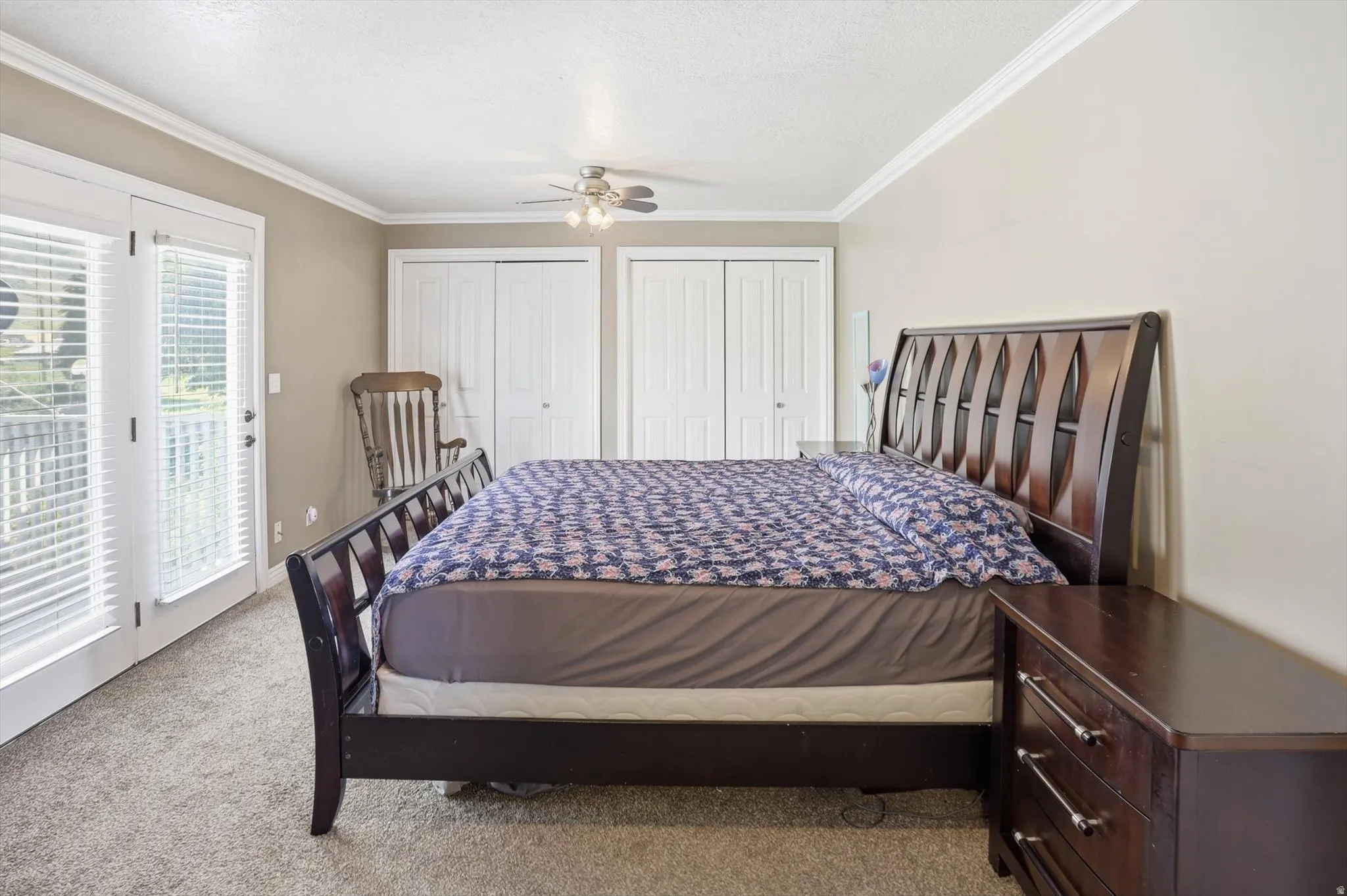 Room featuring a ceiling fan, two sets of white bifold closet doors, and light-colored carpeting