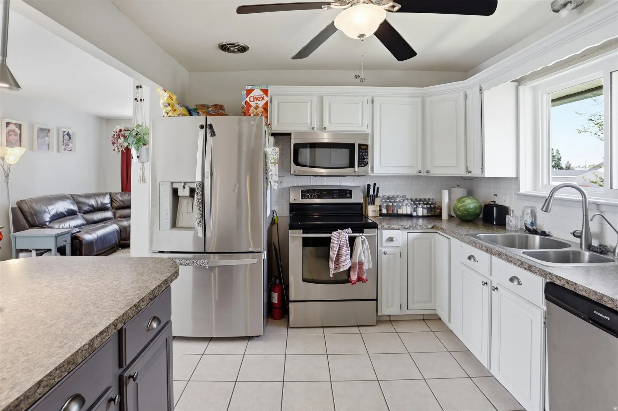 Kitchen featuring white cabinetry, stainless steel appliances, a dual basin sink, and a tiled backsplash