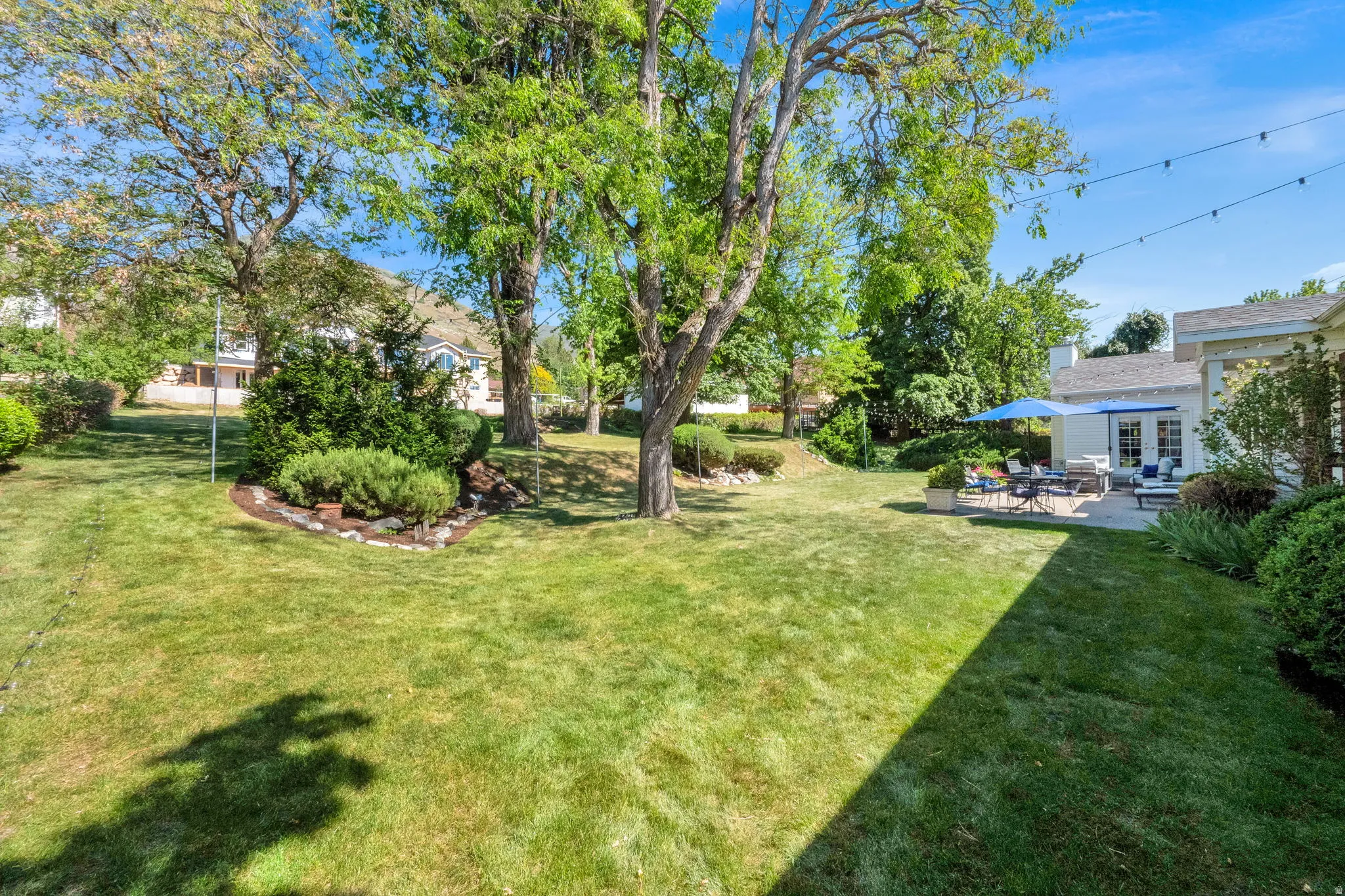 Expansive green lawn with mature trees providing natural shading