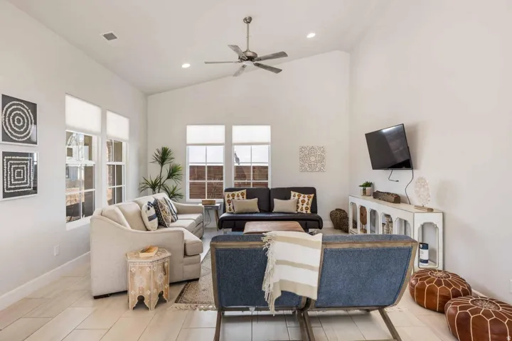Living area featuring vaulted ceilings, recessed lighting, wood-finish flooring, a ceiling fan, and multiple windows