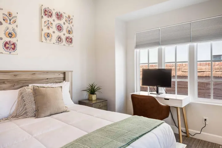 Bedroom featuring a wood-finish headboard, large window with blinds, white trim, and light-colored walls