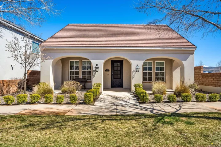 Stucco exterior featuring a red tile roof, arched entryway, and dual windows