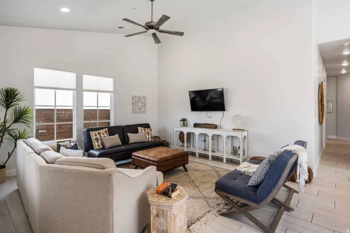 Living area featuring high ceilings, light wood-finish flooring, recessed lighting, and a contemporary ceiling fan