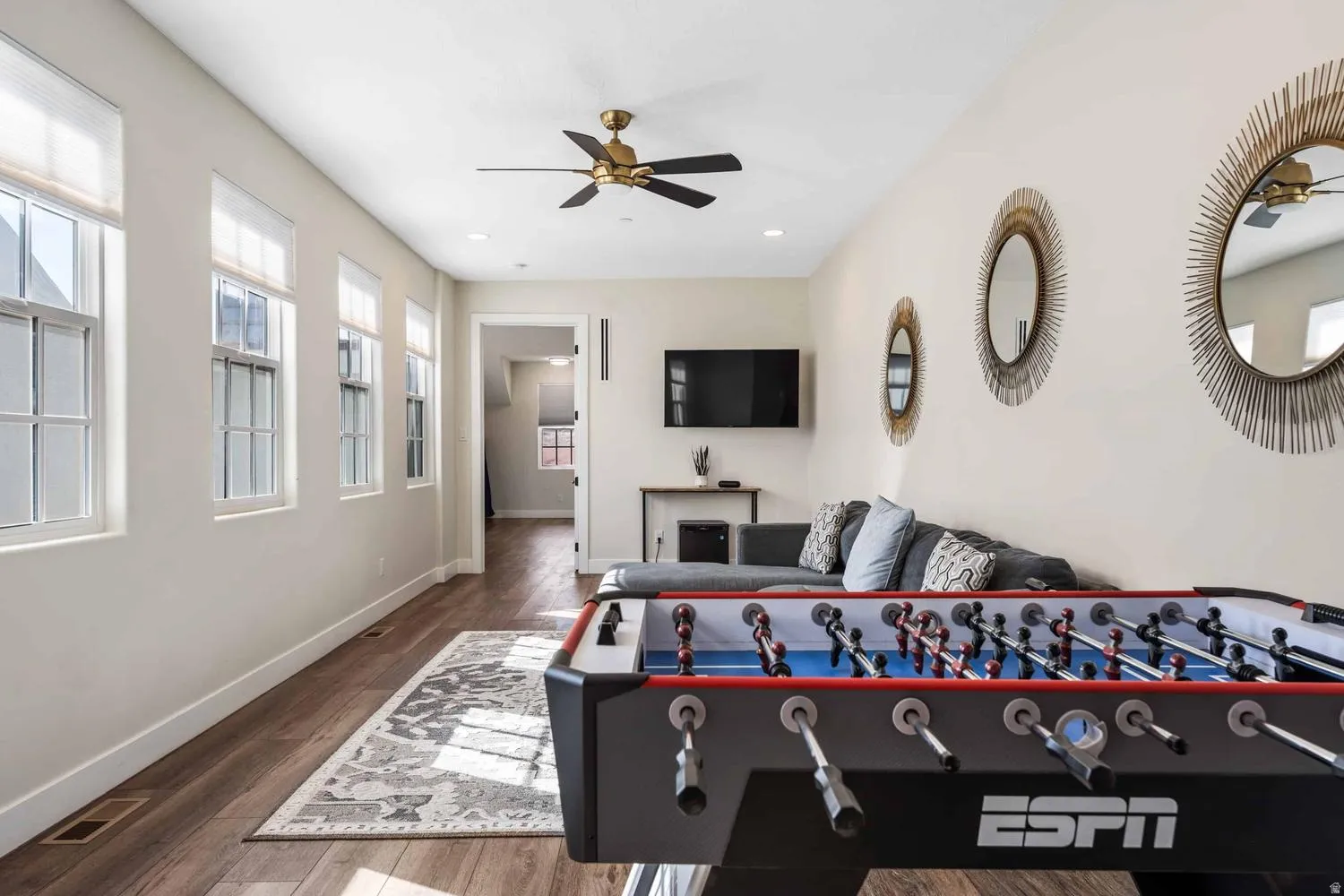 Spacious recreational room featuring wood-finish flooring, a ceiling fan, recessed lighting, and multiple windows with blinds