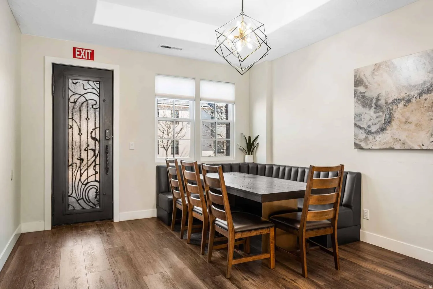 Dining area featuring wood-finish flooring, built-in window seating, and a decorative frosted glass entry door