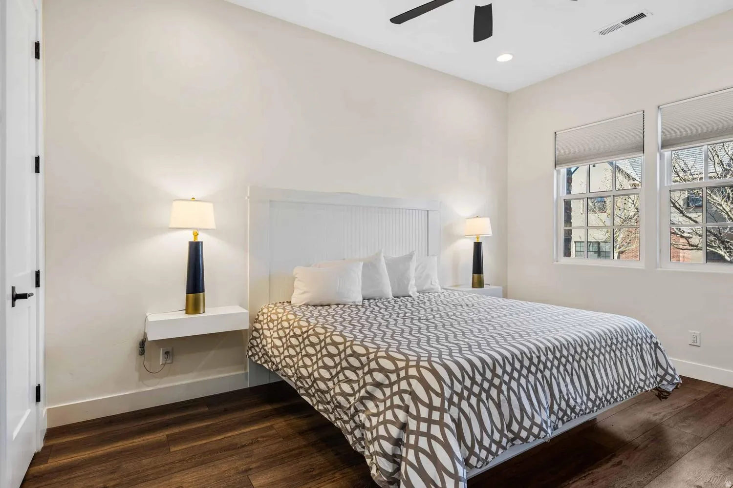 Spacious room featuring wood-finish flooring, white walls, and a ceiling fan