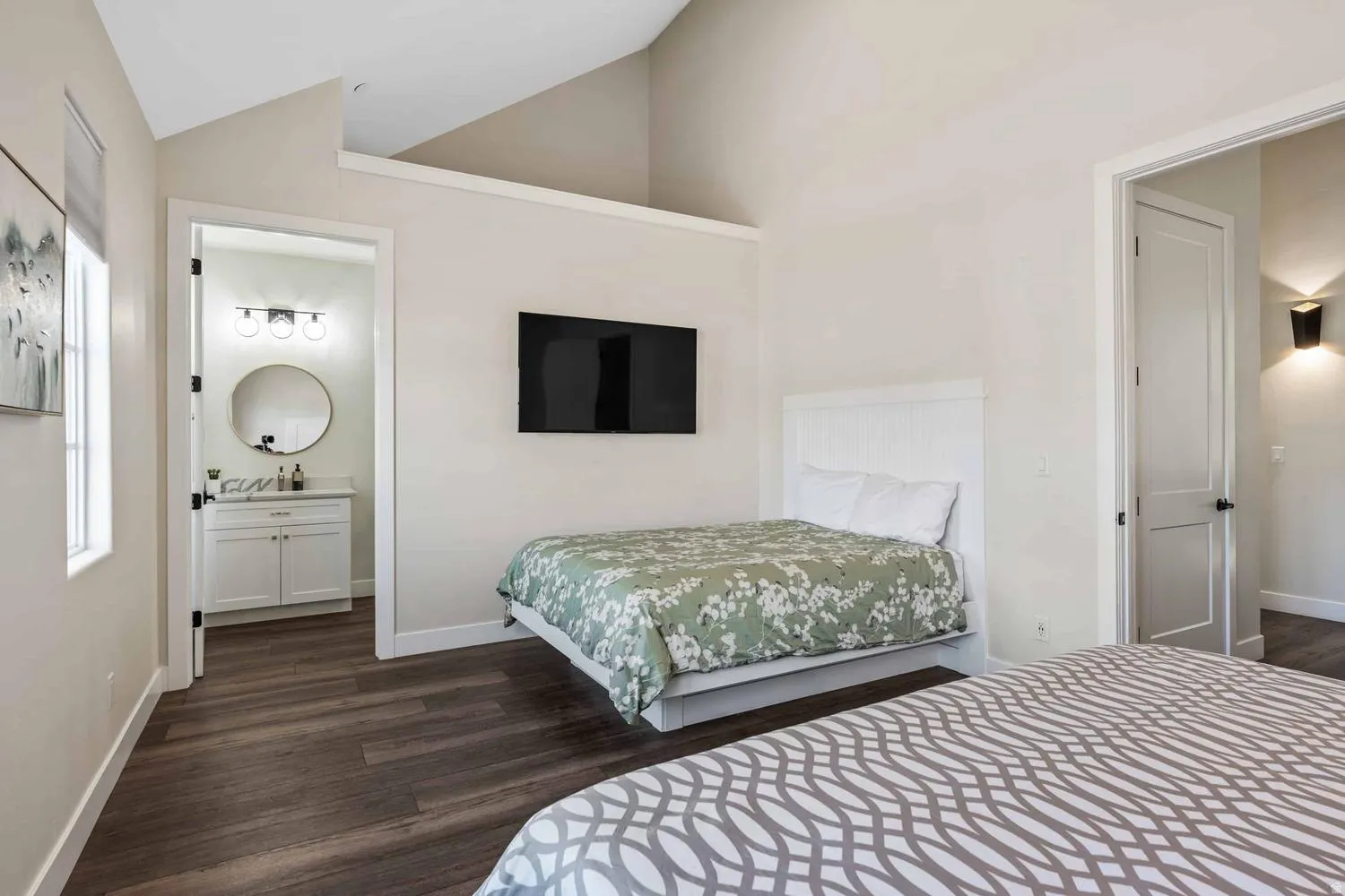 Vaulted ceiling bedroom featuring wood-finish flooring and a built-in wall-mounted television