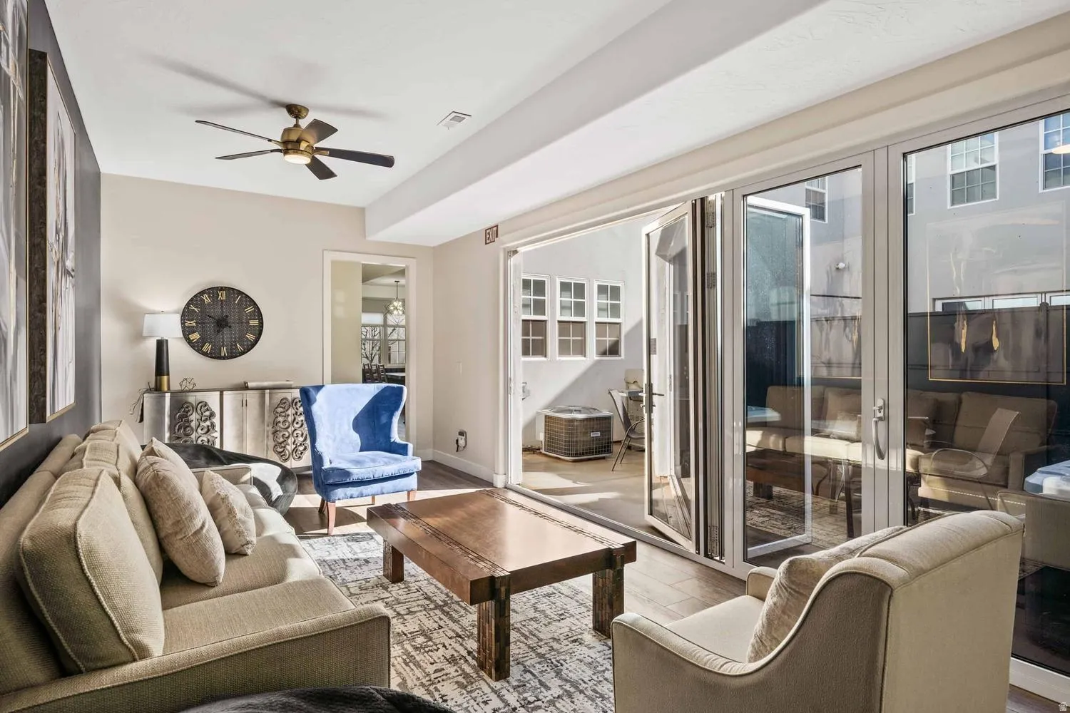 Living area featuring wood-finish flooring, a ceiling fan, and a light-toned accent wall