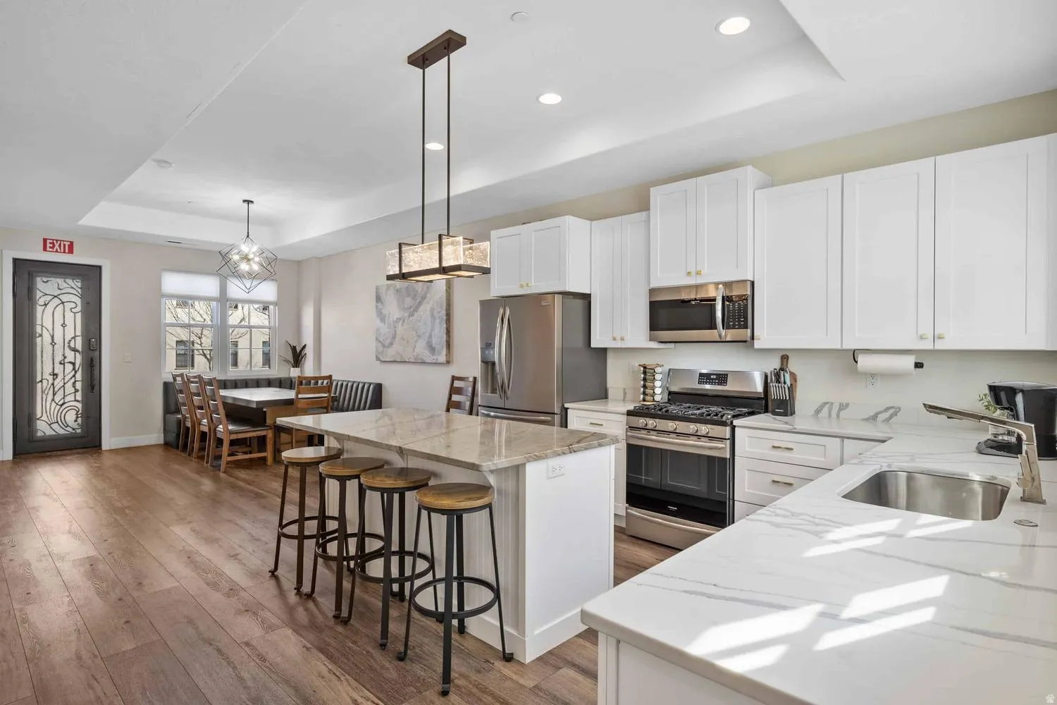 Open-concept kitchen featuring white cabinetry, stainless steel appliances, and two distinct countertop surfaces