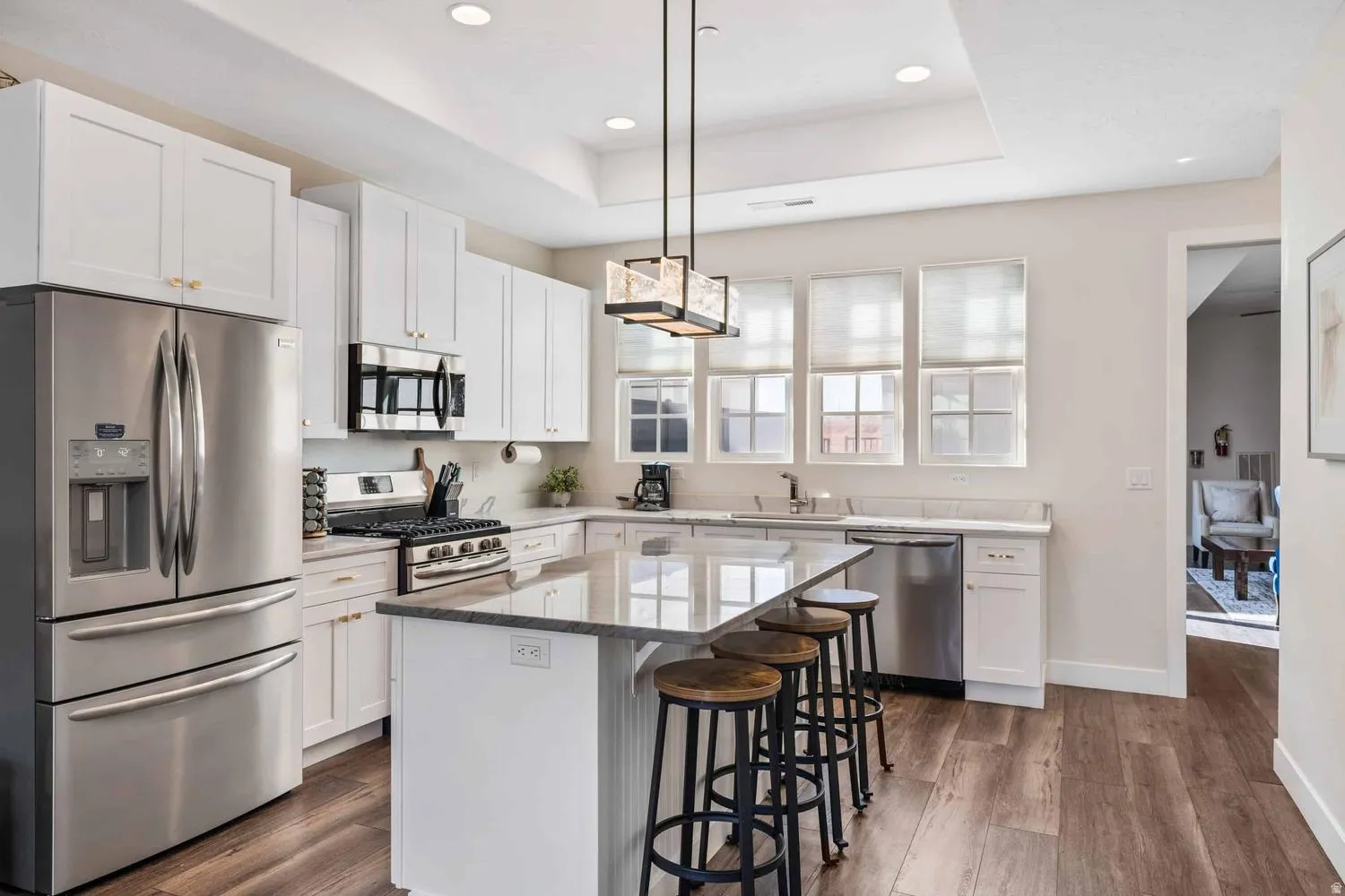 Kitchen featuring white cabinetry, stainless steel appliances, a center island with countertop seating, and wood-finish flooring
