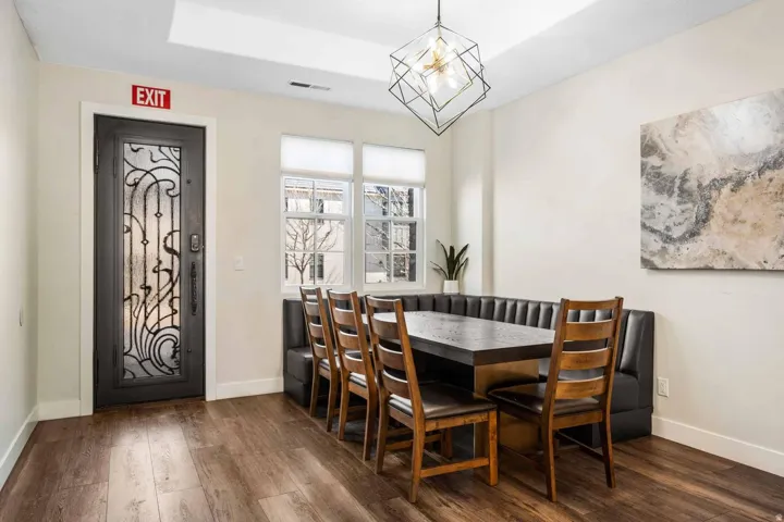 Dining area featuring wood-finish flooring, built-in window seating, and a decorative frosted glass entry door