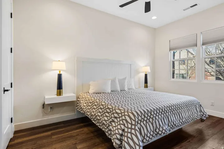 Spacious room featuring wood-finish flooring, white walls, and a ceiling fan