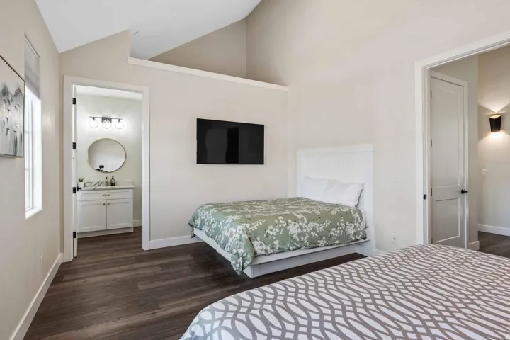 Vaulted ceiling bedroom featuring wood-finish flooring and a built-in wall-mounted television