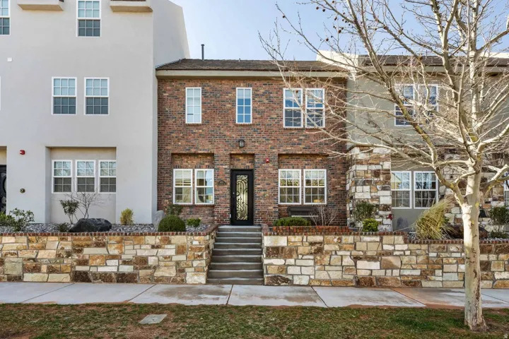 Brick and stucco townhouse exterior featuring multi-pane windows and a decorative glass entry door