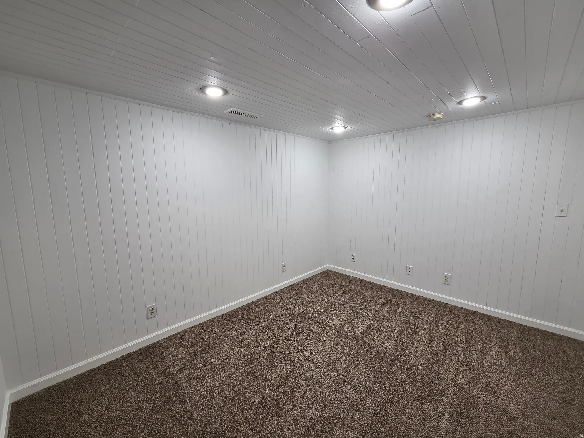 Room featuring shiplap walls, recessed lighting, and brown textured carpeting