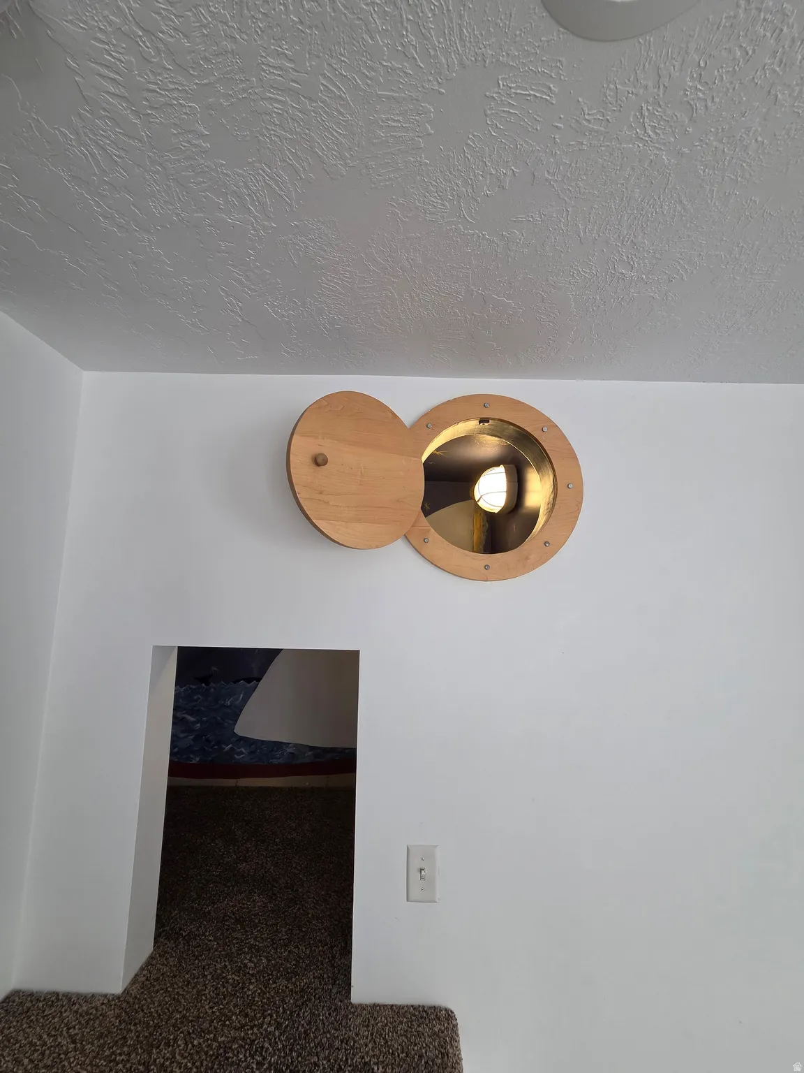 Circular wooden portal with a hinged cover and interior light fixture