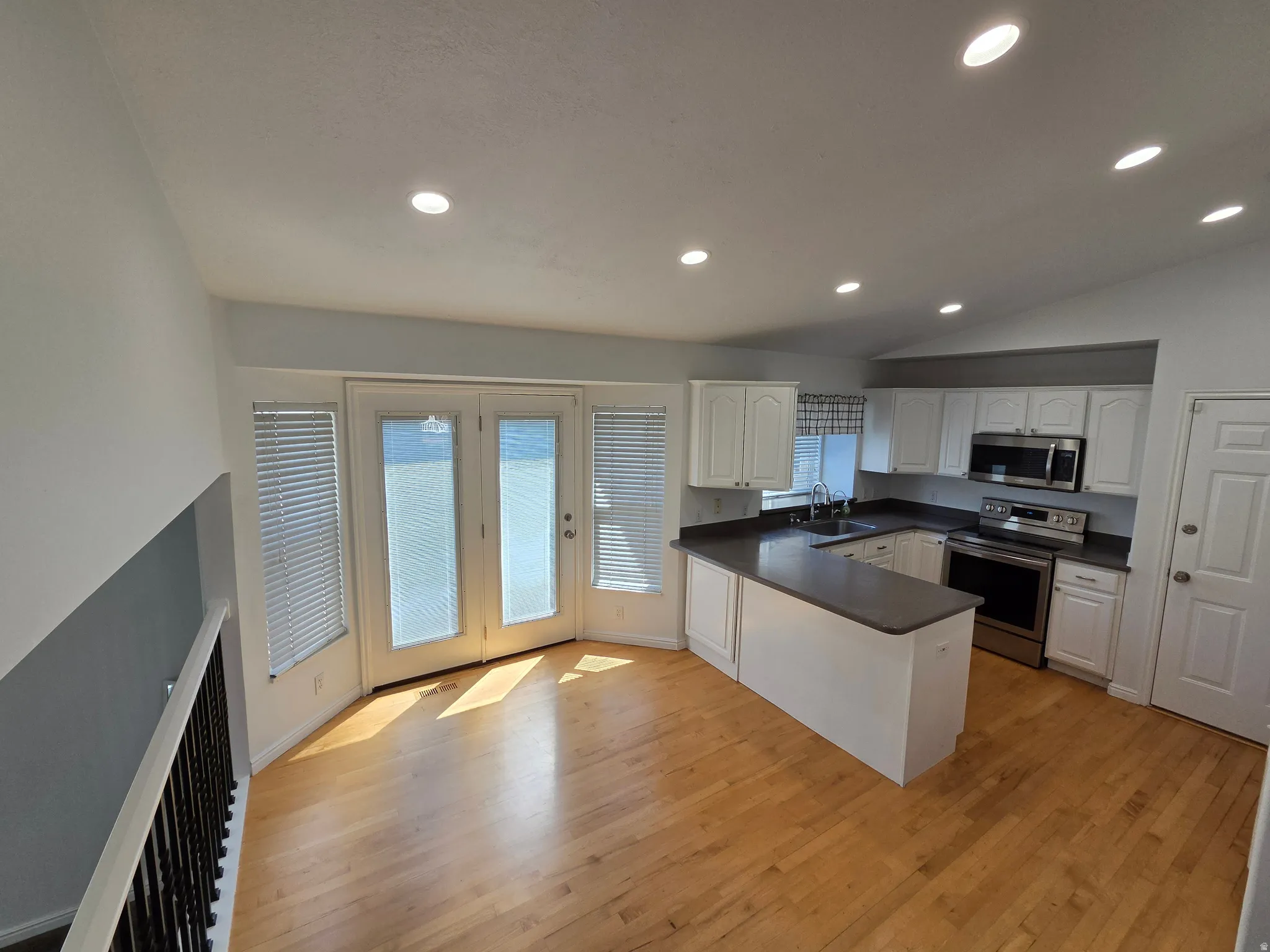 Open-concept kitchen with recessed lighting, white cabinetry, dark countertops, and stainless steel appliances