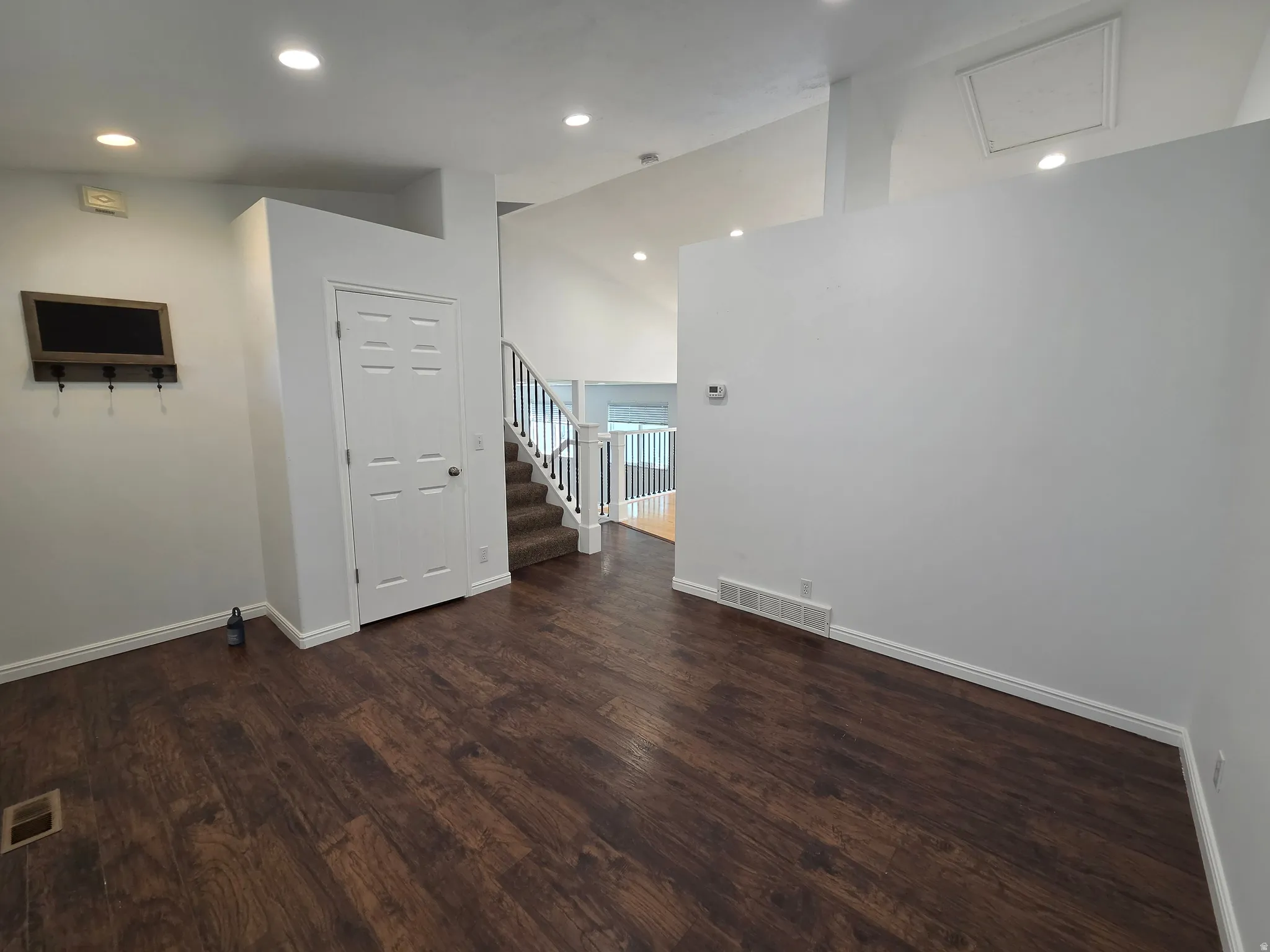 Spacious interior featuring wood-finish flooring, recessed lighting, white trim, and a prominent staircase with white railings