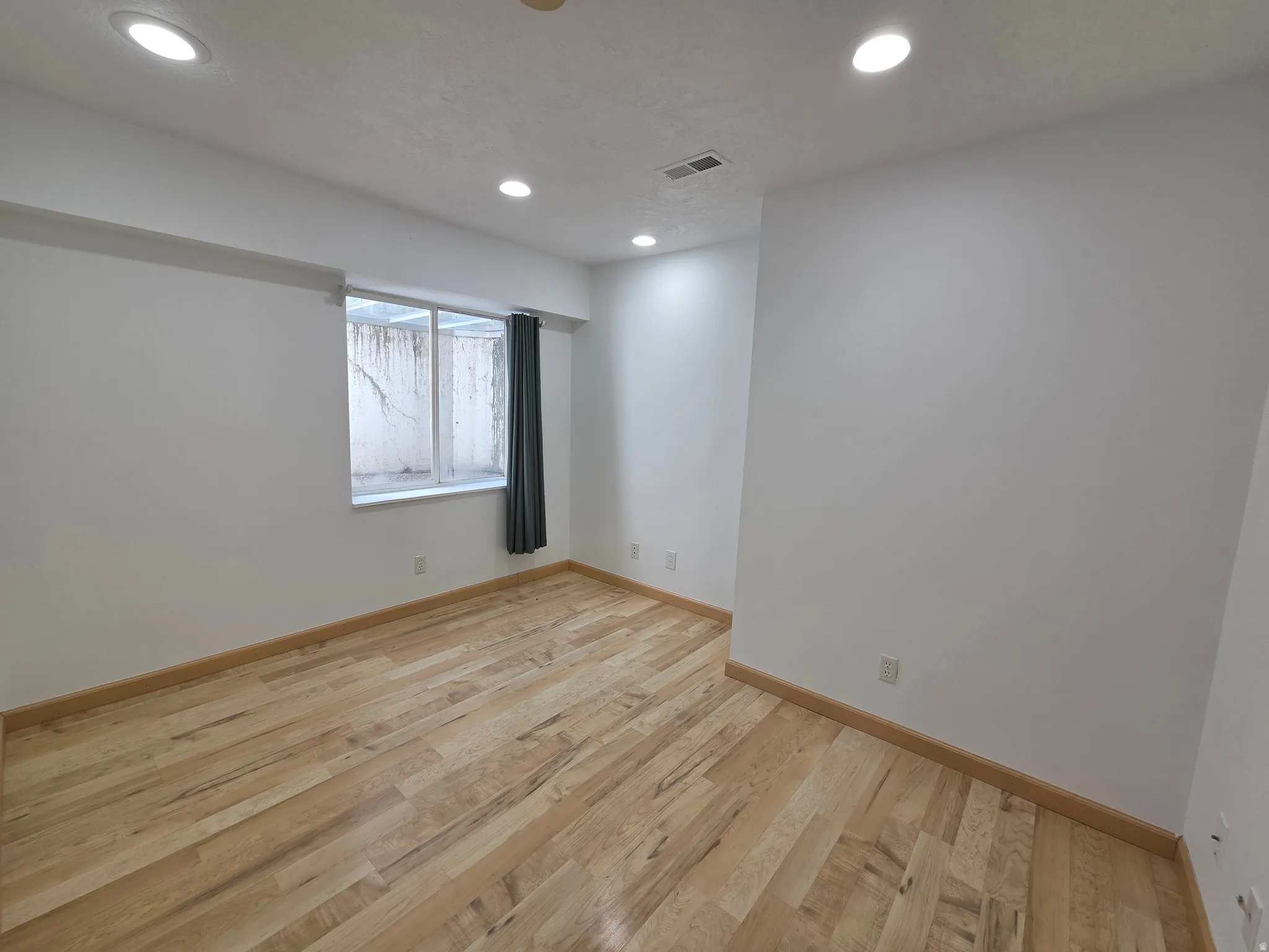 Room featuring wood-finish flooring, recessed ceiling lighting, and a window