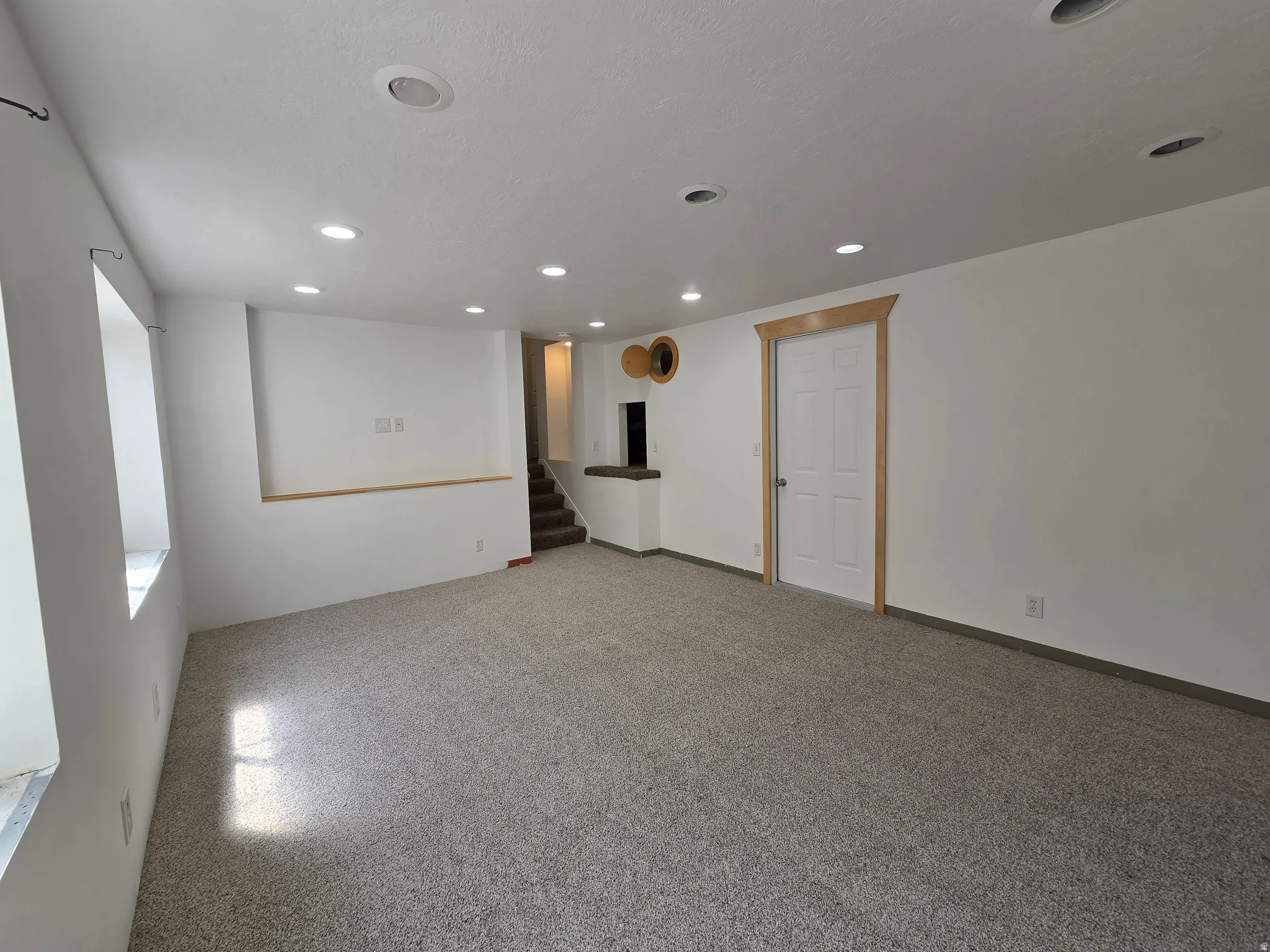 Spacious lower-level room featuring light gray carpeting and recessed lighting