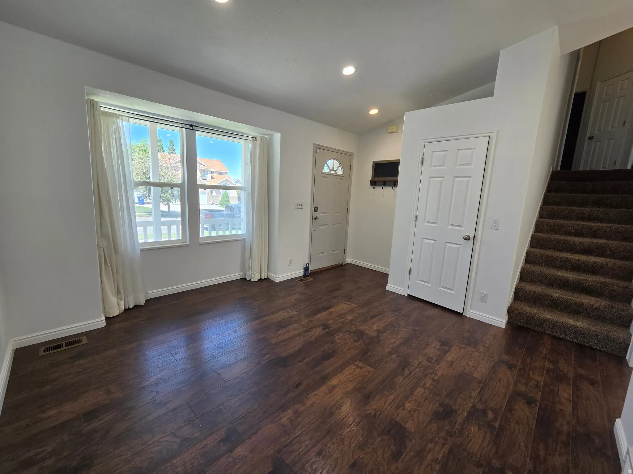 Spacious entry with wood-finish flooring, recessed lighting, and a prominent front window