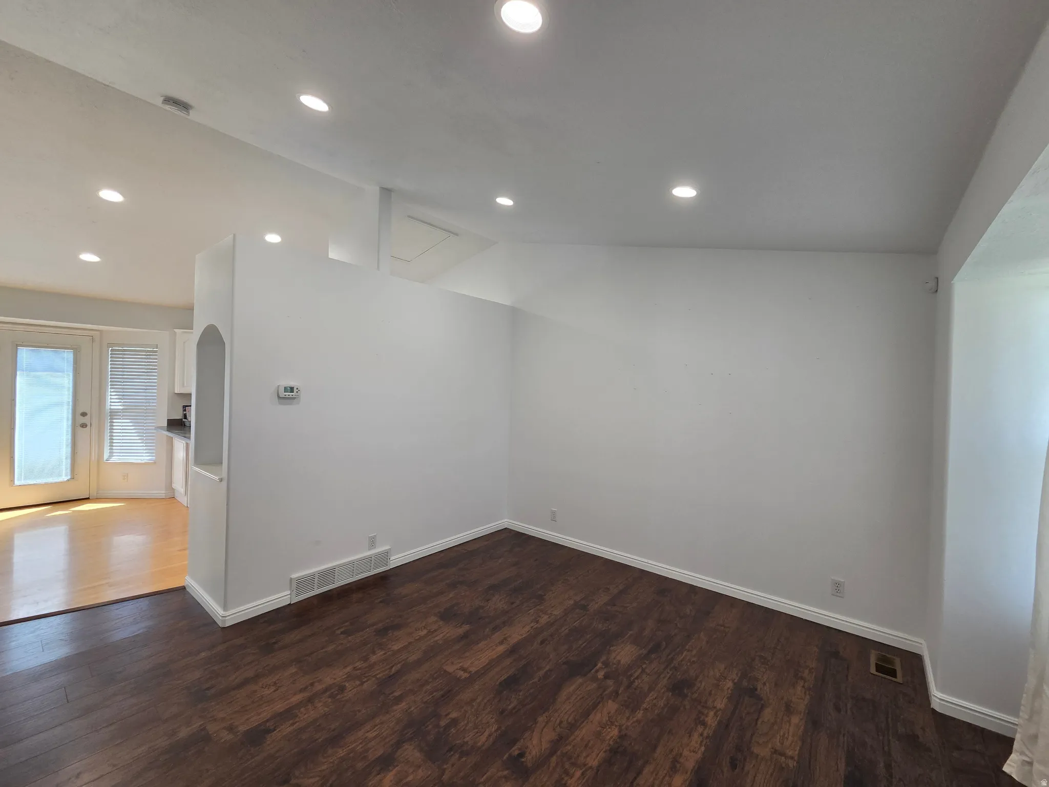 Spacious room featuring rich wood-finish flooring, recessed lighting, and white baseboards
