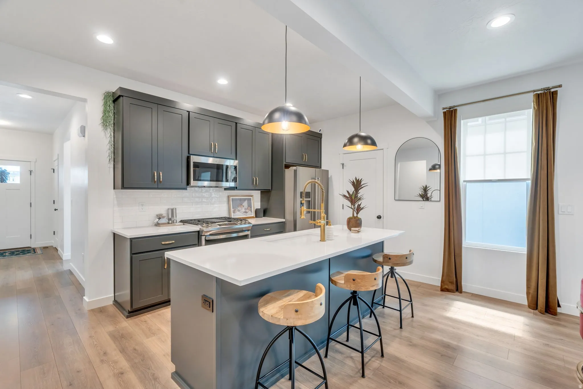 Modern kitchen featuring dark cabinetry, stainless steel appliances, and a white subway tile backsplash