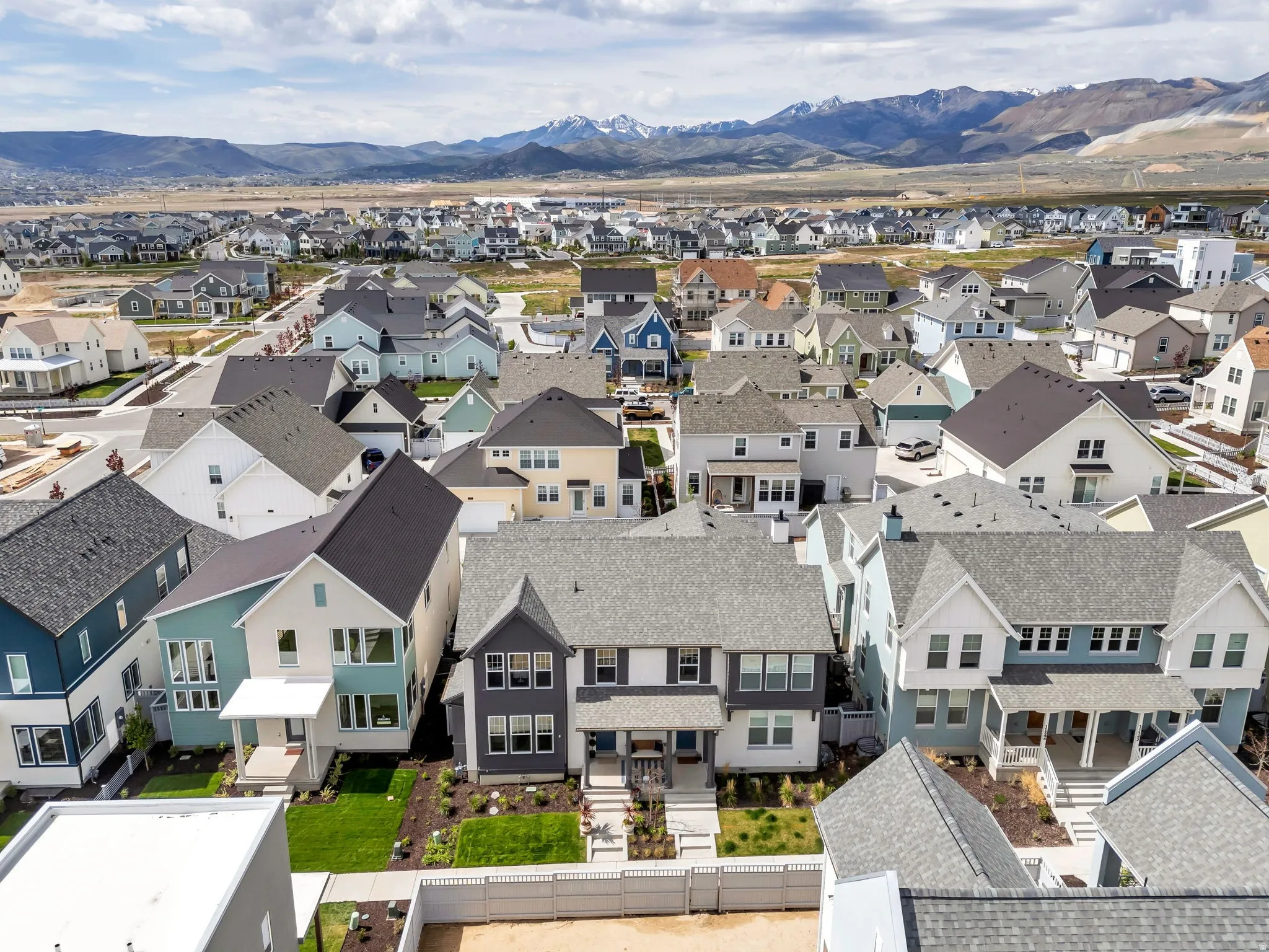 Modern residential development featuring a diverse collection of homes, paved streets, and a backdrop of distant mountains