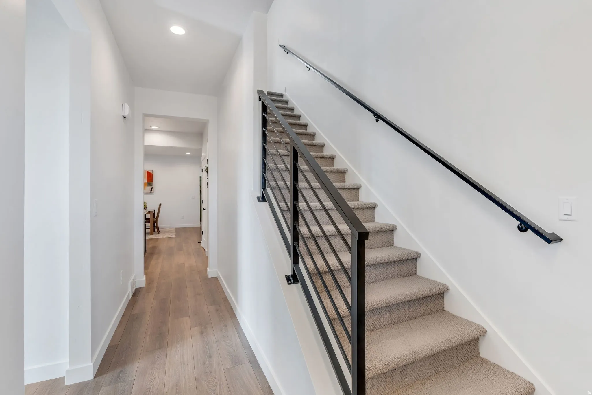 Modern staircase with a contemporary black metal railing and carpeted treads