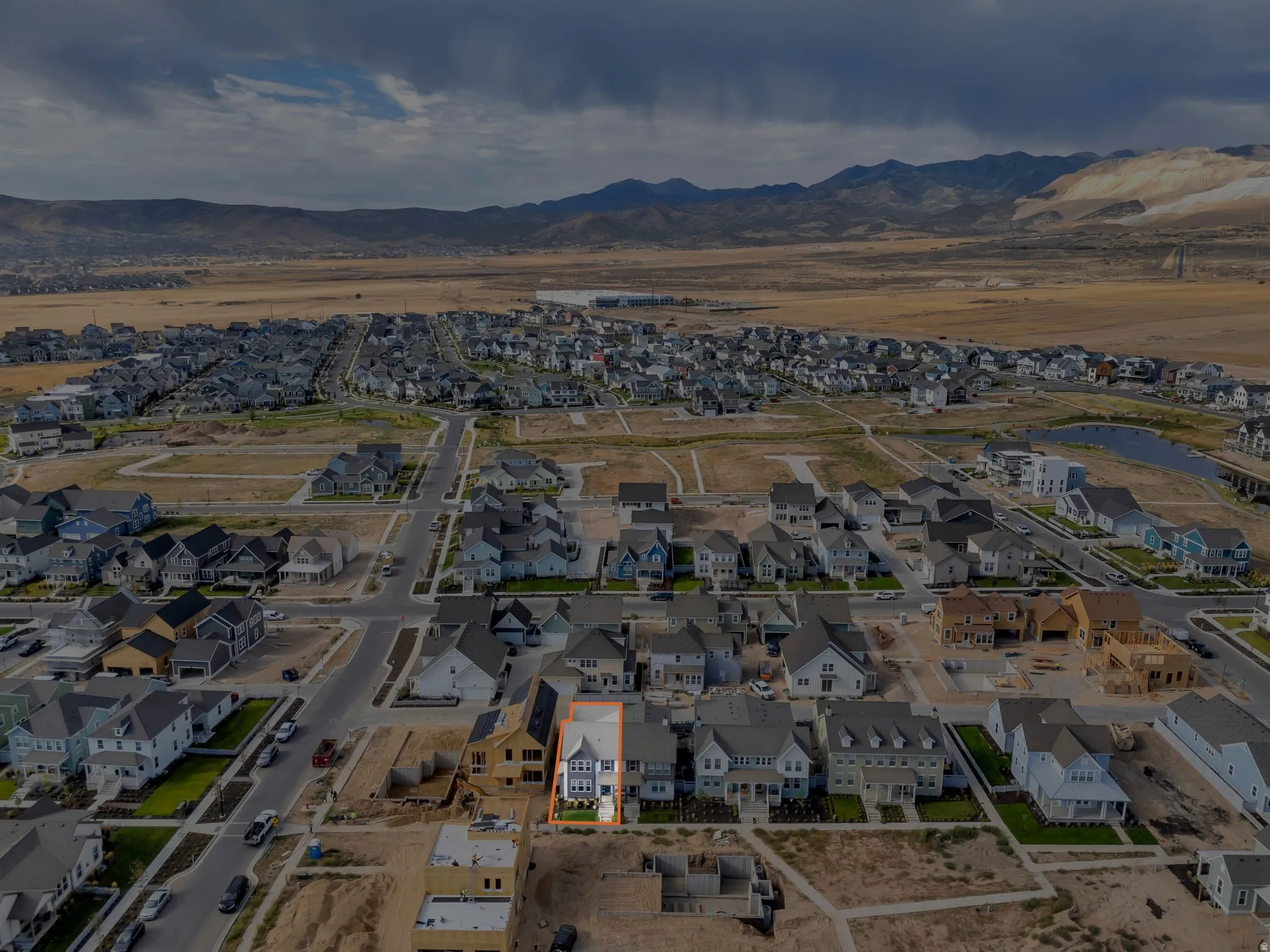 Aerial perspective of a developing residential community, featuring a multi-story property with a light-colored facade