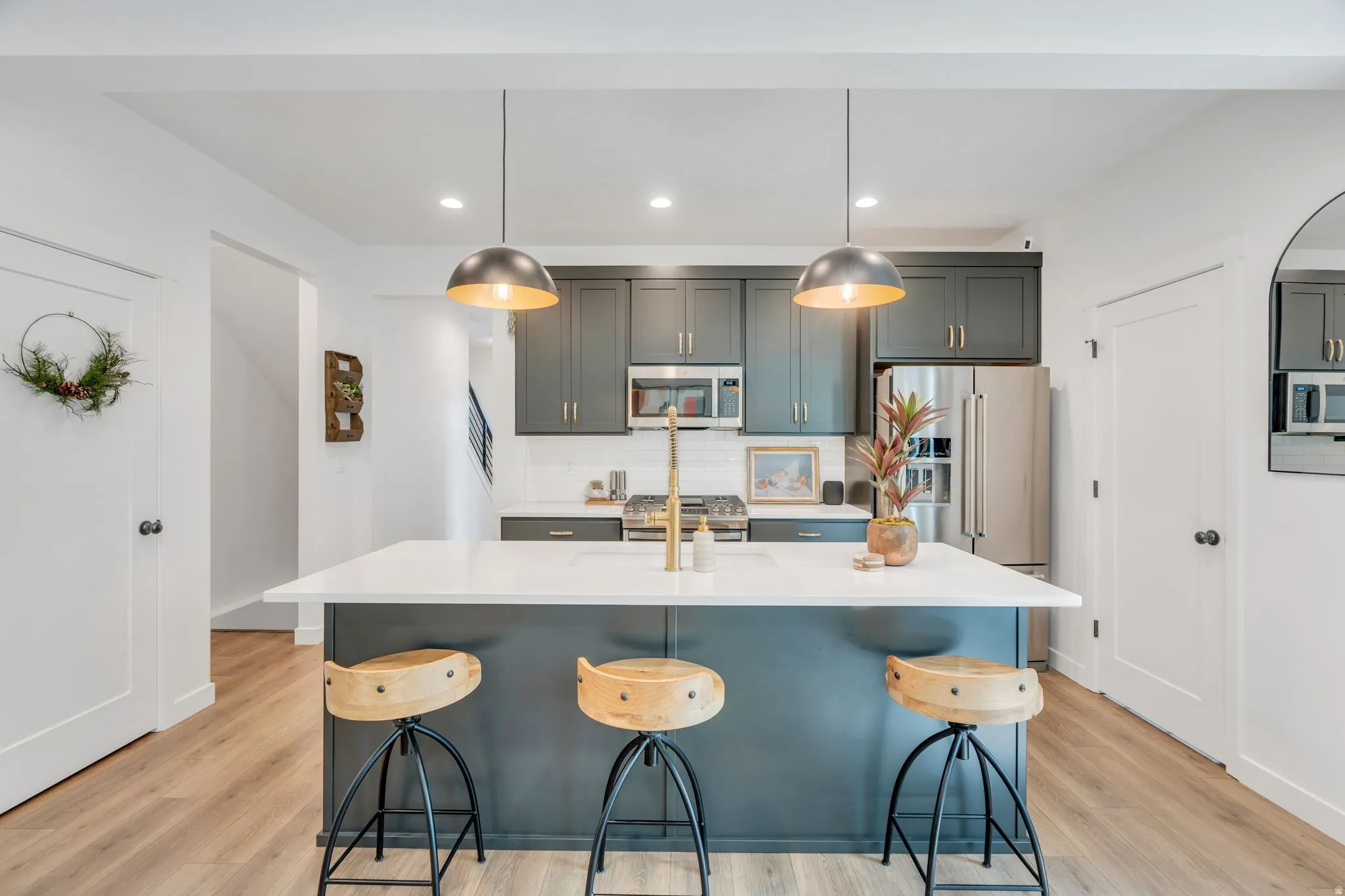 Open-concept kitchen featuring an island with seating, dark cabinetry, stainless steel appliances, and wood-finish flooring