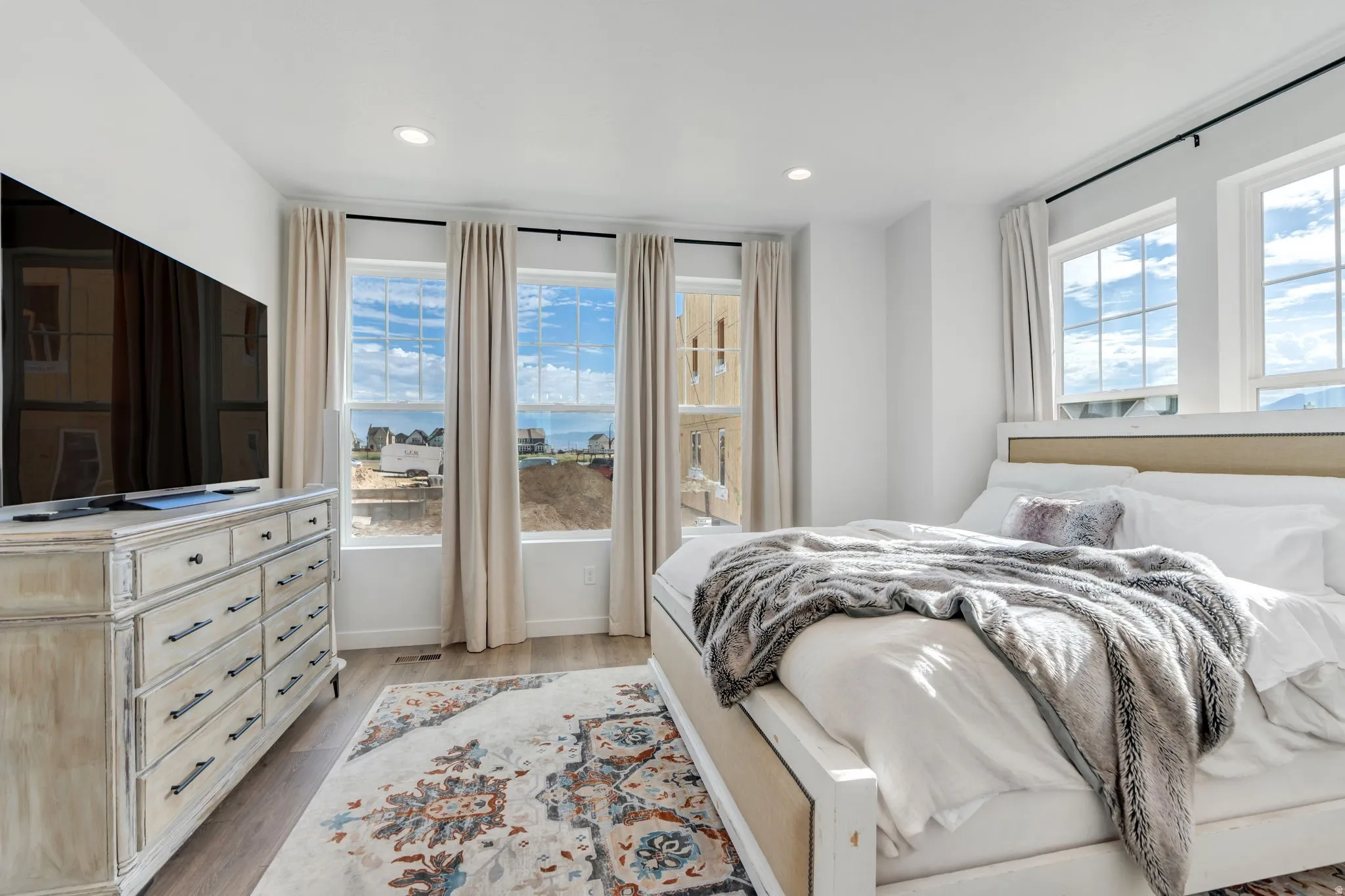 Bedroom featuring three large windows, recessed lighting, and wood-finish flooring