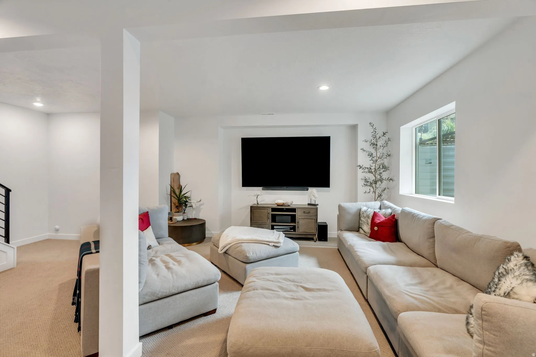 Spacious living area featuring neutral carpeting, recessed lighting, and a large window providing ambient light