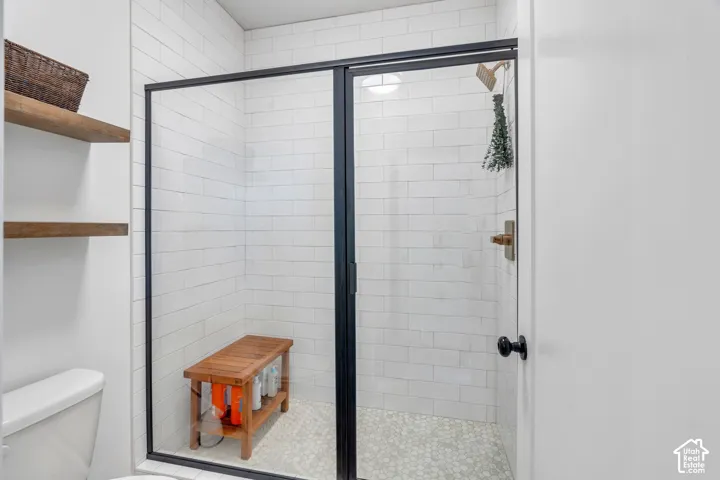 Walk-in shower featuring white subway wall tile, mosaic tile flooring, a matte black-framed glass enclosure, and metallic fixtures