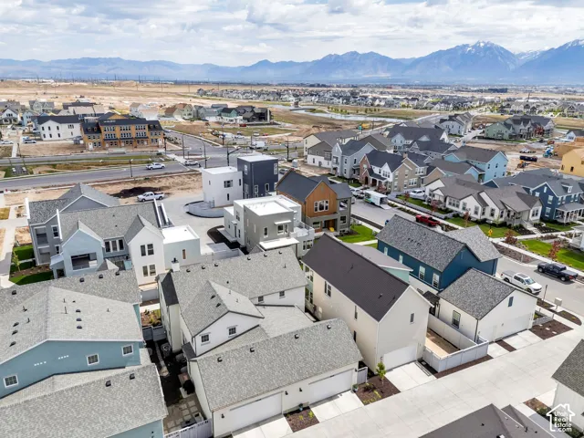 Aerial perspective of a multi-structure residential community featuring pitched shingle roofing, attached garages, and a mountainous horizon backdrop