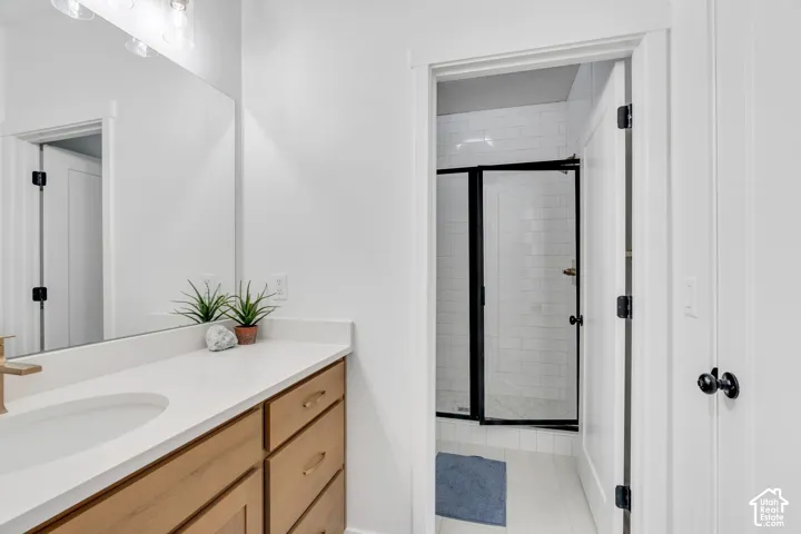 Bathroom featuring light wood-finish vanity cabinetry with brushed gold hardware, a white countertop, an undermount sink, and a large wall mirror