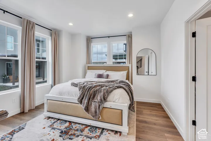 Bedroom featuring wood-finish flooring, recessed lighting, and multiple windows with grid detailing