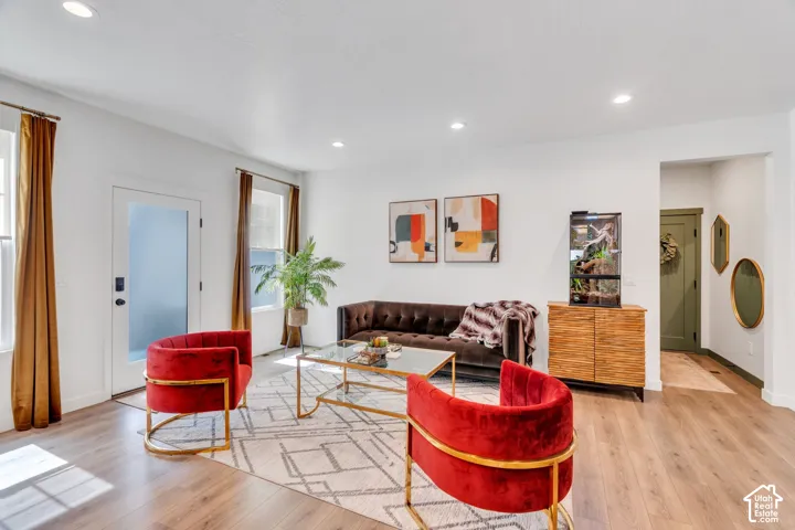 Bright living area featuring wood-finish flooring, recessed lighting, and a white interior door with frosted glass