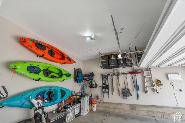 Spacious garage featuring a concrete floor, light gray walls, white ceiling, overhead storage racks, and wall-mounted storage systems