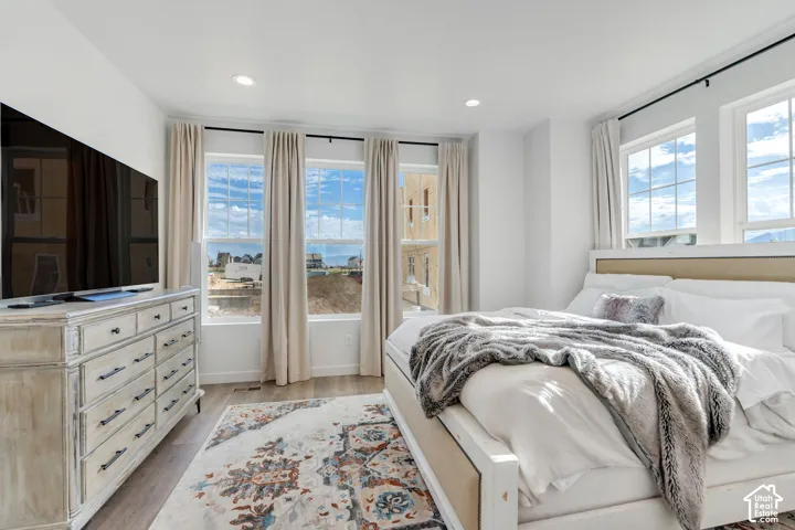 Bedroom featuring three large windows, recessed lighting, and wood-finish flooring