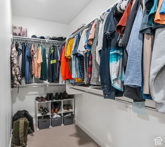 Walk-in closet featuring tiered white wire shelving, dual hanging rods, and integrated shoe cubby storage