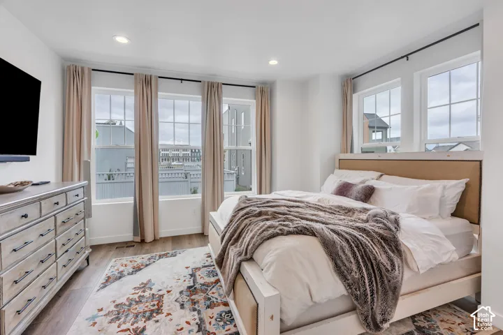 Bedroom featuring wood-finish flooring, recessed lighting, and multiple large windows with muntins