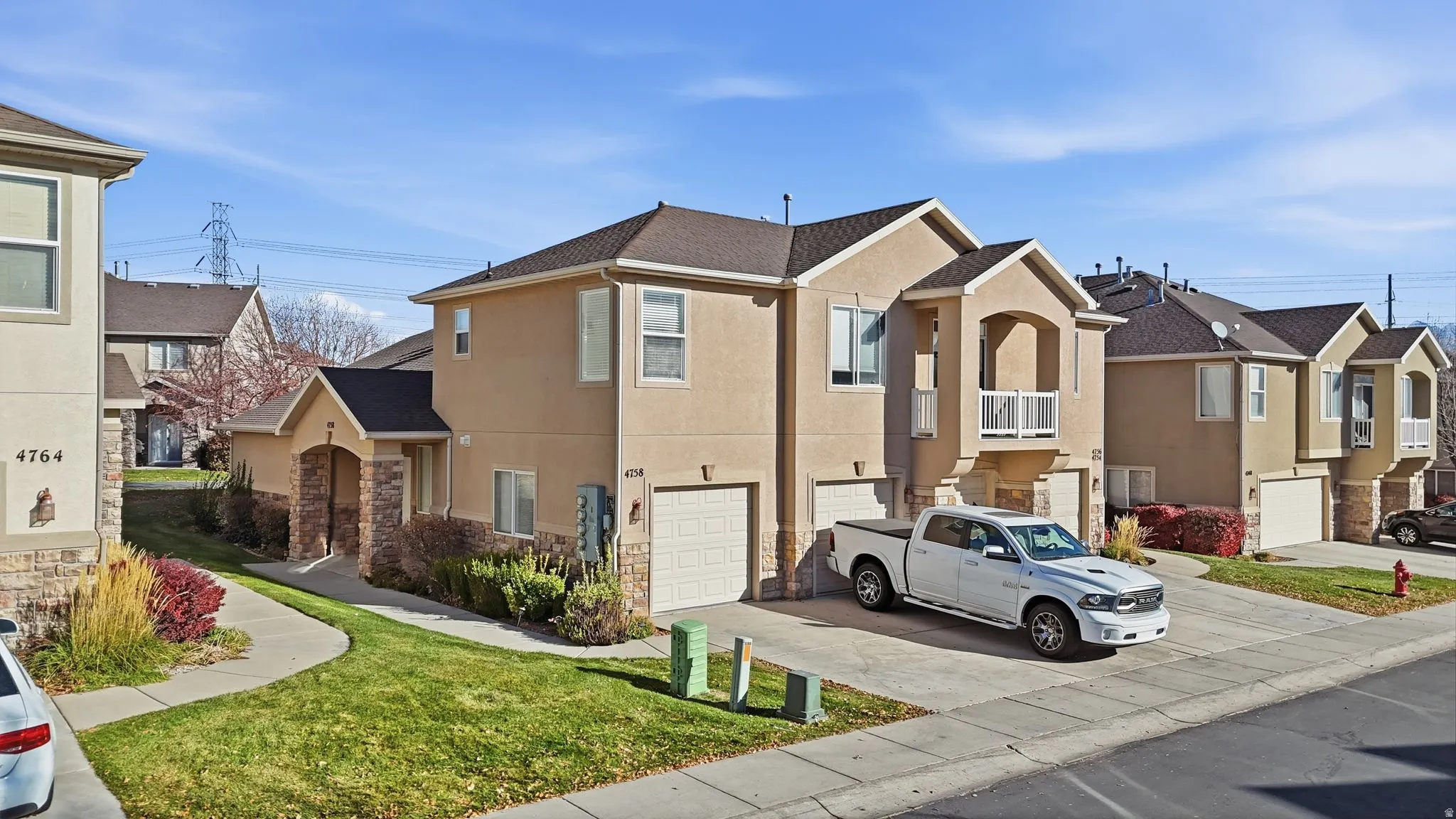 Stucco exterior with stone accents, featuring a two-car garage and a private balcony
