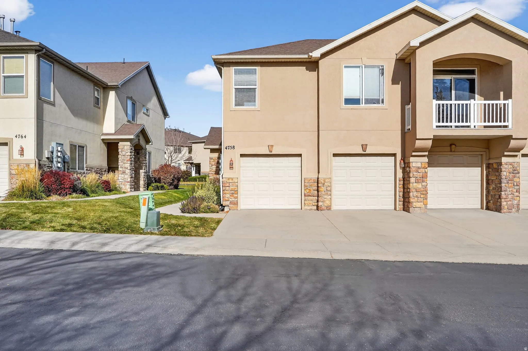 Multi-unit residence featuring neutral stucco siding and stone veneer accents