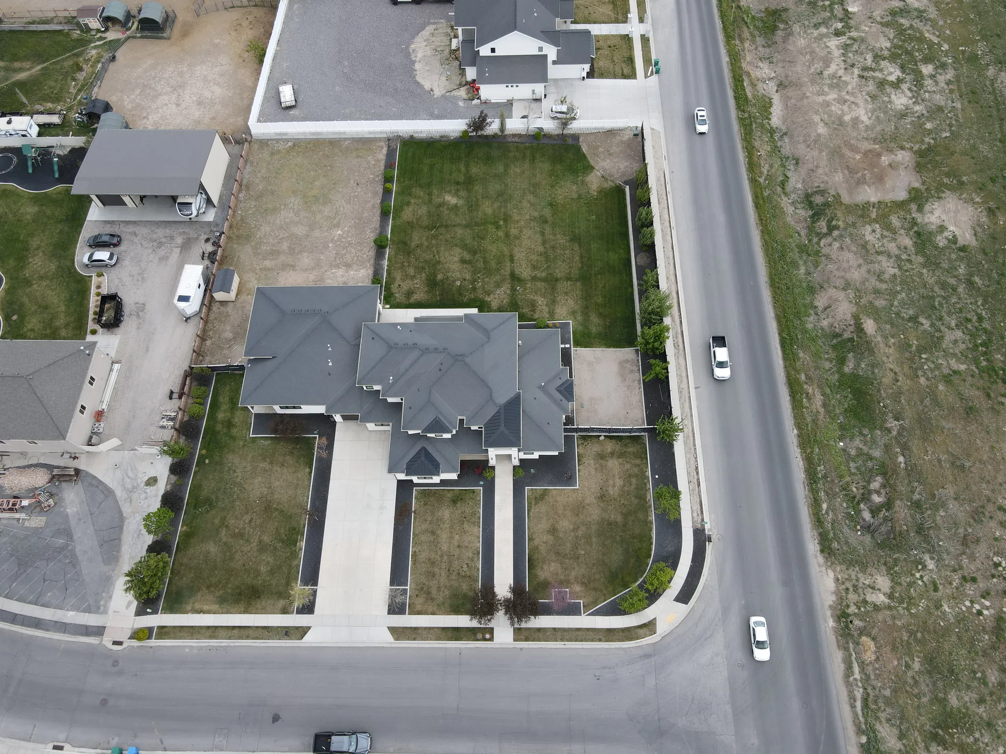 Contemporary residence featuring a dark shingle roof, light-toned exterior, and an extensive concrete driveway